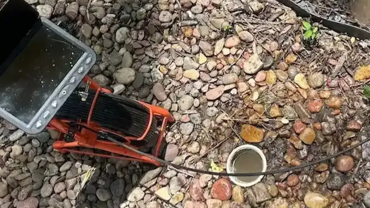 Sewer camera and cable positioned beside an exterior cleanout