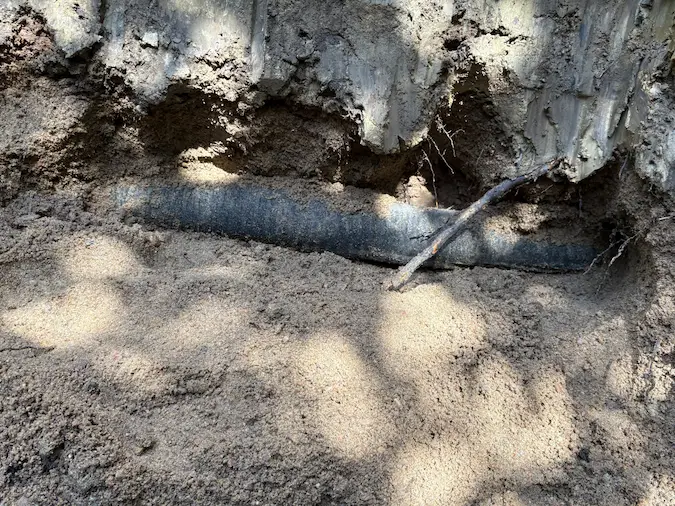 Exposed drain tile along a foundation wall during drainage repair