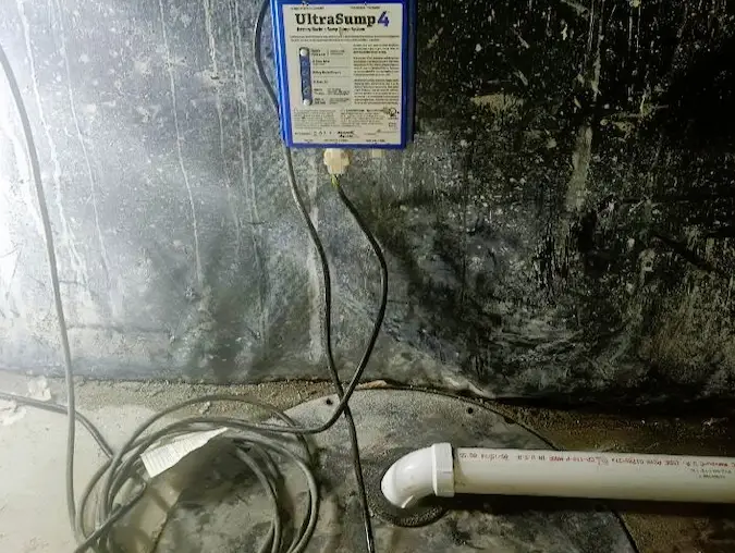 Sump pump backup control system mounted near a basement wall