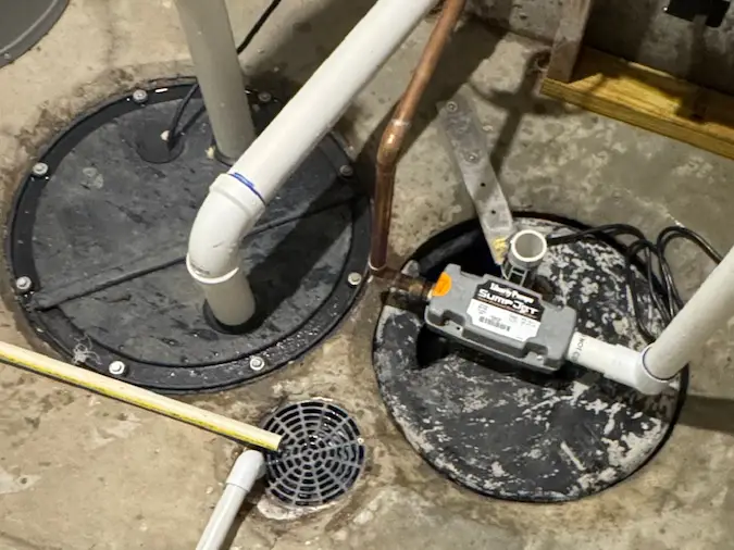 Water-powered backup sump pump installation near a basement basin