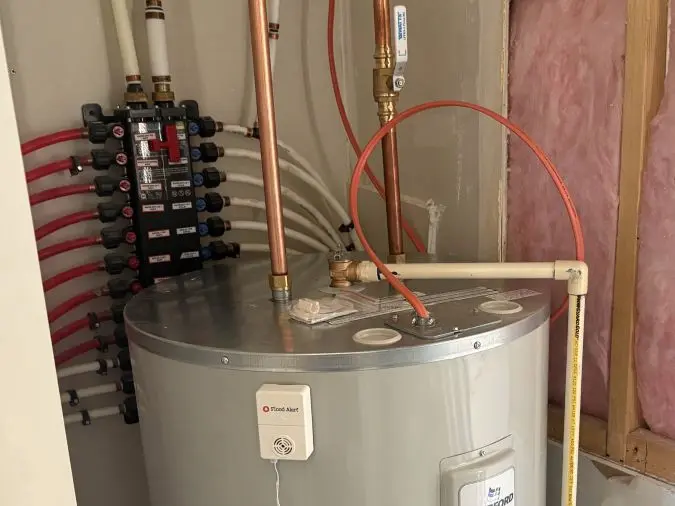 Storage water heater with connected piping and a nearby plumbing manifold