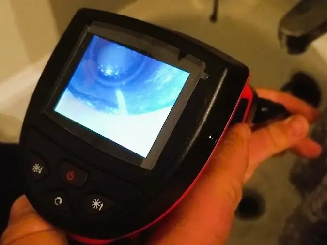 Handheld drain camera inspecting an accessible household drain line