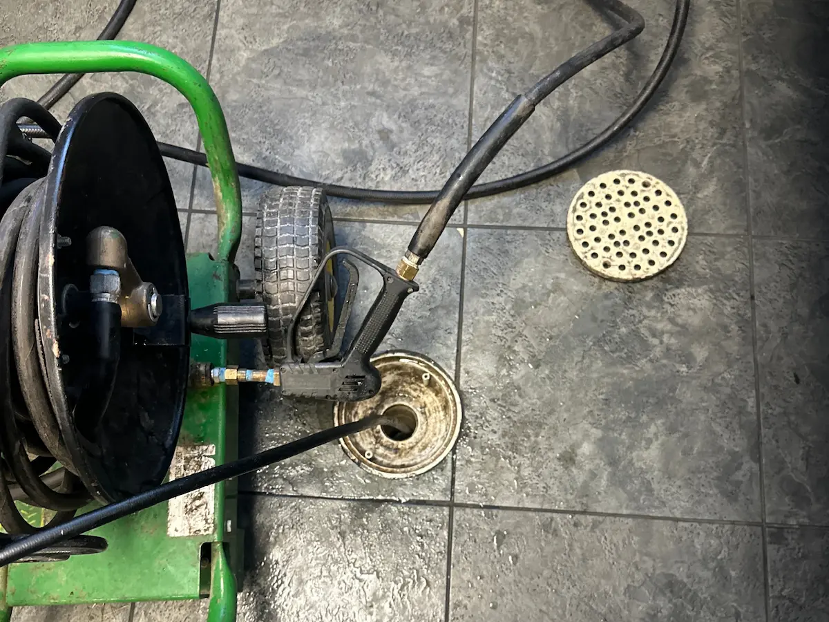 Professional hydro-jetting equipment cleaning an indoor floor drain