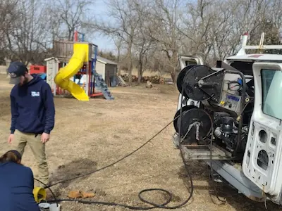 PD Plumbing technicians preparing hydro-jetting equipment beside a service vehicle