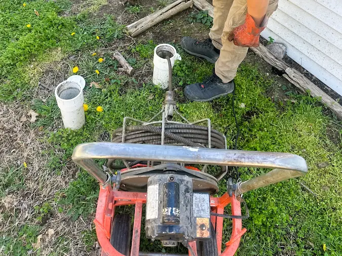 Main-sewer cable machine positioned at a two-way exterior cleanout