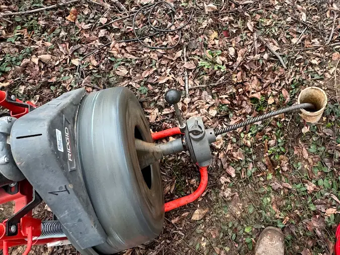 Professional sewer cable machine feeding cable through an exterior cleanout