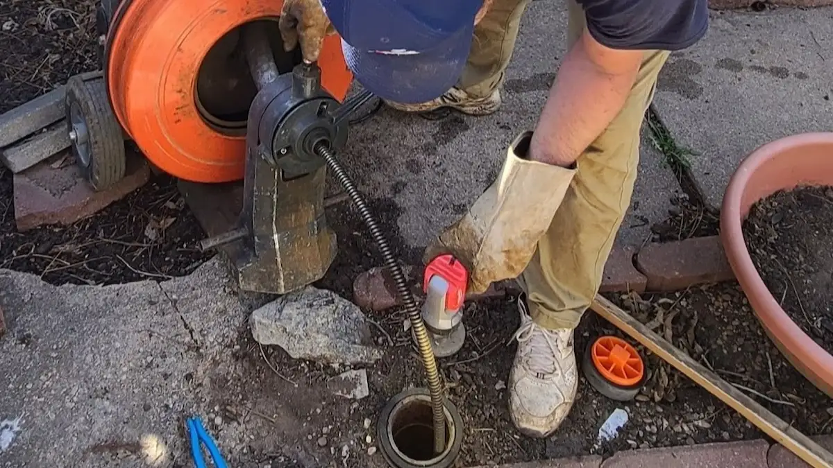 PD Plumbing technician cleaning a main sewer line through an exterior cleanout in Wichita