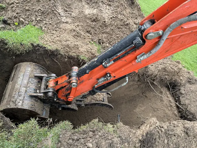Mini excavator digging a trench for sewer line repair