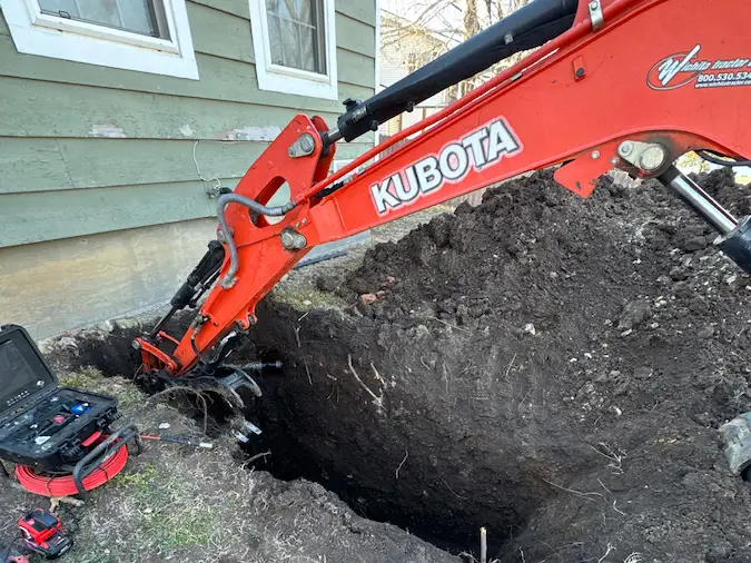 Sewer line repair excavation with camera equipment near the trench