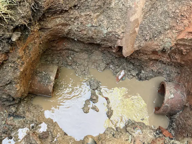 Broken clay sewer pipe exposed before a localized repair