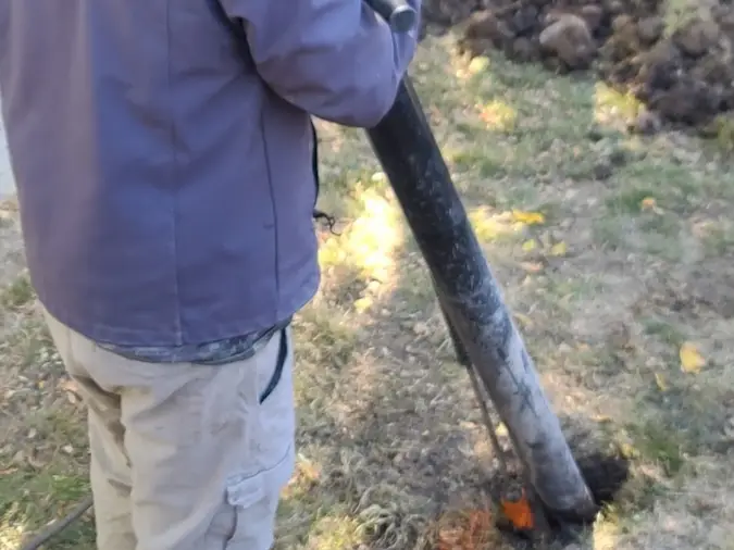 Technician using hydro excavation to expose a sewer repair area