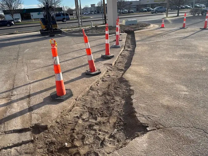 Commercial sewer line excavation route through asphalt with traffic cones