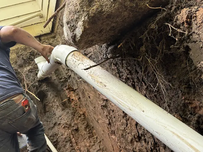 PD Plumbing crew installing a new PVC sewer connection beside a structure