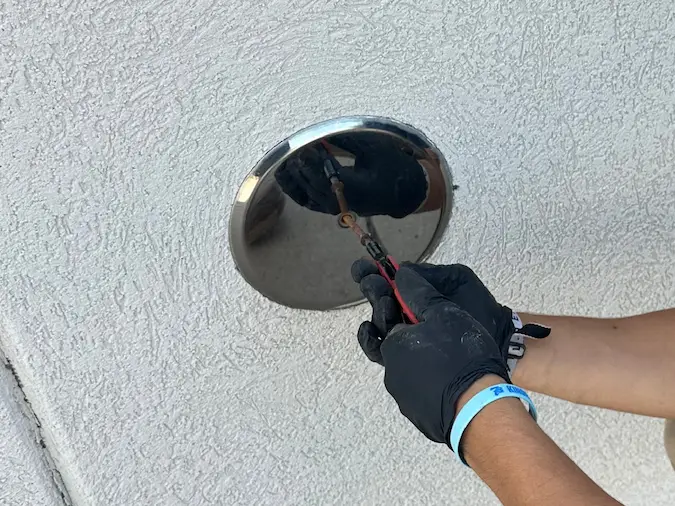PD Plumbing technician feeding inspection equipment through a wall sewer cleanout