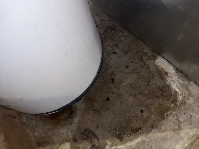 Water visible on the floor around the base of a storage water heater